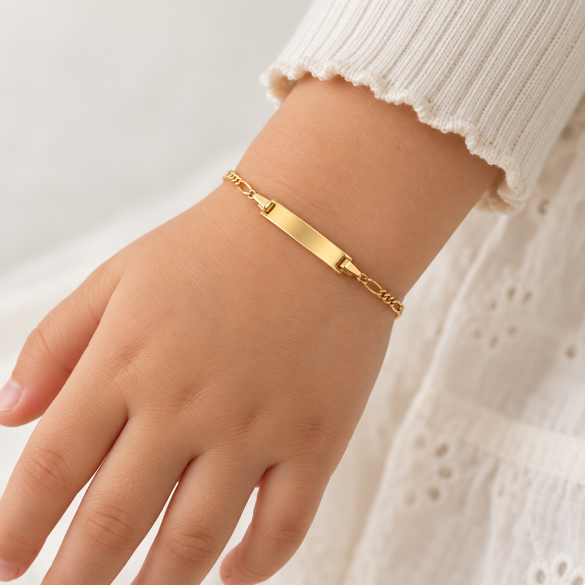 Kinder ID-Armband aus 585 Gelbgold mit Gravurplatte am Handgelenk getragen