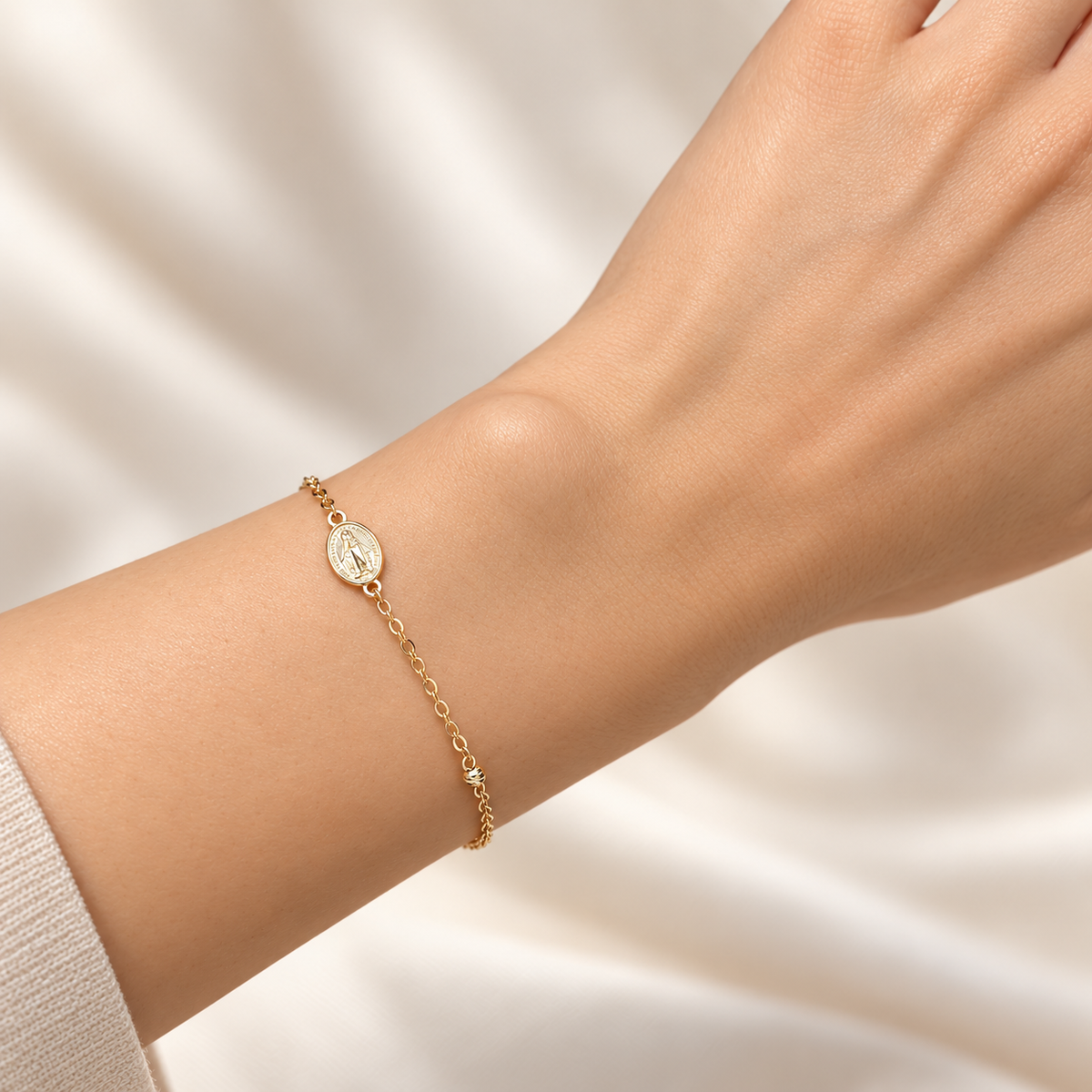 Zartes Armband aus 585 Gelbgold mit ovaler Marienmedaille an einem Damenhandgelenk getragen.