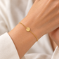 Feines Armband aus 585 Gelbgold mit runder Gravurplatte am Handgelenk getragen.