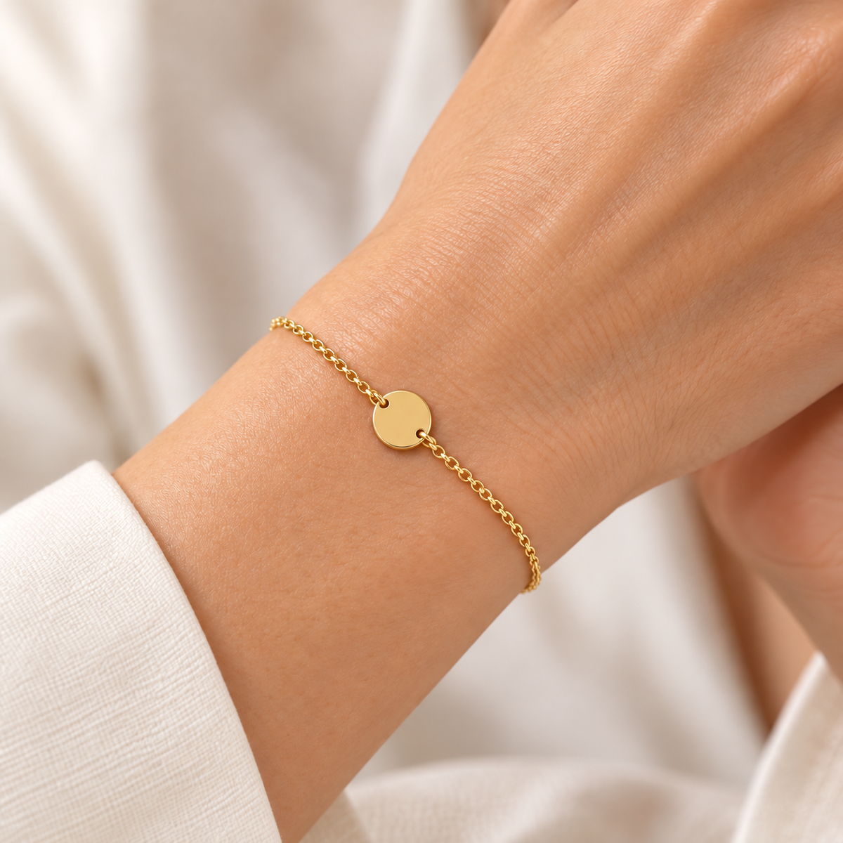 Feines Armband aus 585 Gelbgold mit runder Gravurplatte am Handgelenk getragen.
