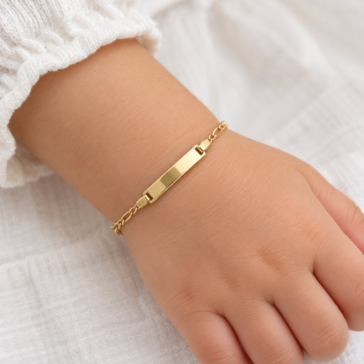 Babyarmband aus 585 Gelbgold mit Gravurplatte und Figarokette am Kinderhandgelenk getragen