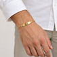 Figaro-Armband aus 585 Gelbgold mit glänzender Gravurplatte an einem Herrenhandgelenk getragen.