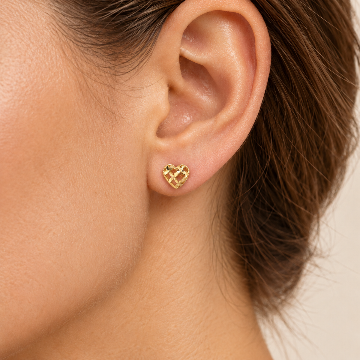 Kleiner Herz-Ohrstecker aus 585 Gelbgold mit filigranem Durchbruchmuster und ca. 5,5 mm Größe am Ohr getragen.