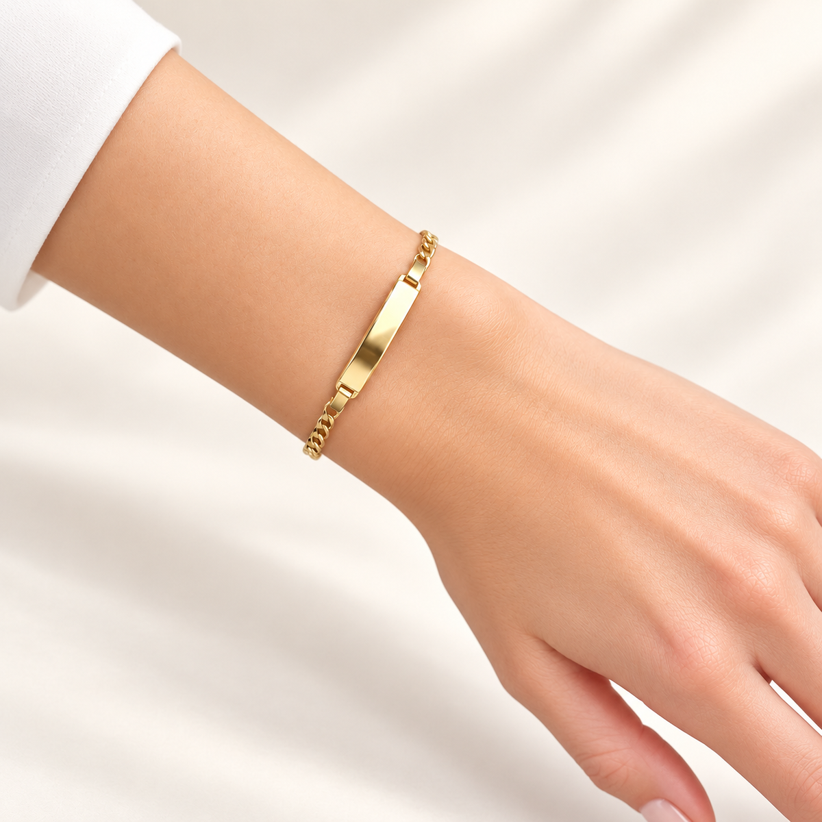 Panzerarmband aus 585 Gelbgold mit länglicher Gravurplatte an einem Damenhandgelenk getragen.