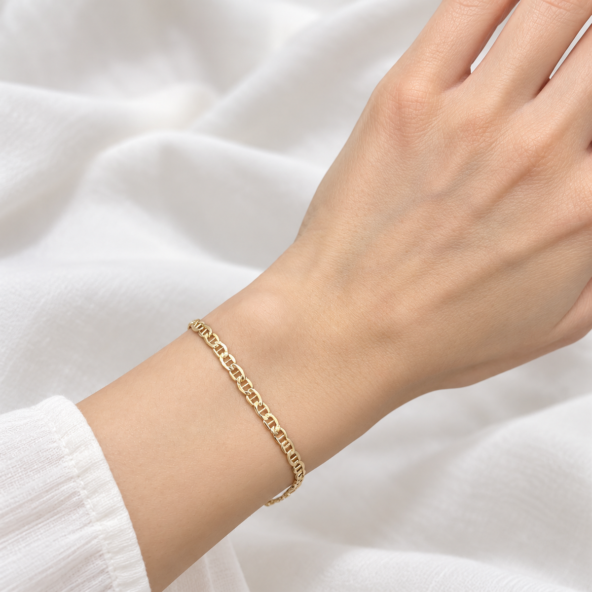 3,5 mm breites Stäbchenpanzer-Armband aus 585 Gelbgold, an einem Damenhandgelenk zu einem weißen Oberteil getragen.