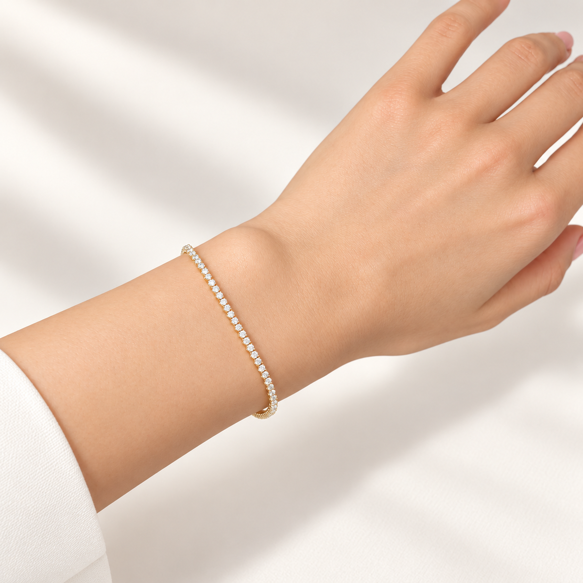 Tennisarmband aus 585 Gelbgold mit funkelnder Zirkoniareihe am Handgelenk vor hellem Hintergrund getragen.